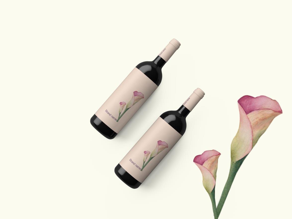 Two wine bottles with pale pink labels beside a painted calla lily